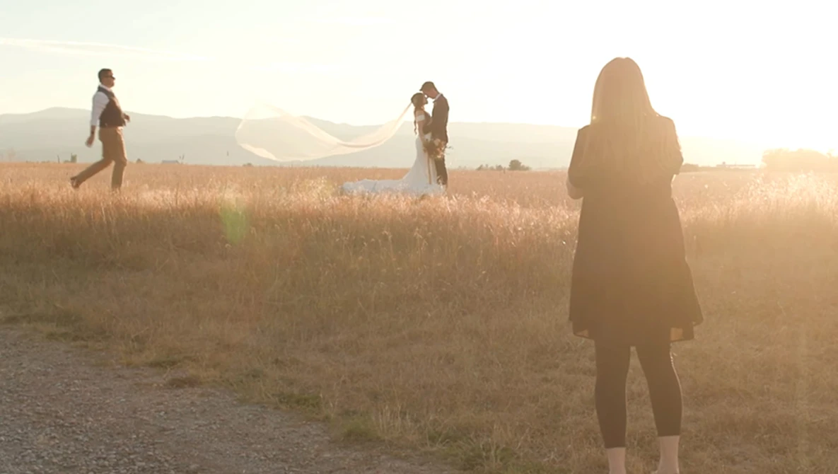 Four people standing in a dry, golden field at golden hour with backlighting creating silhouettes.