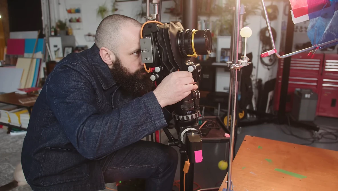 Photographer using a large format camera on a tripod in a workshop studio.