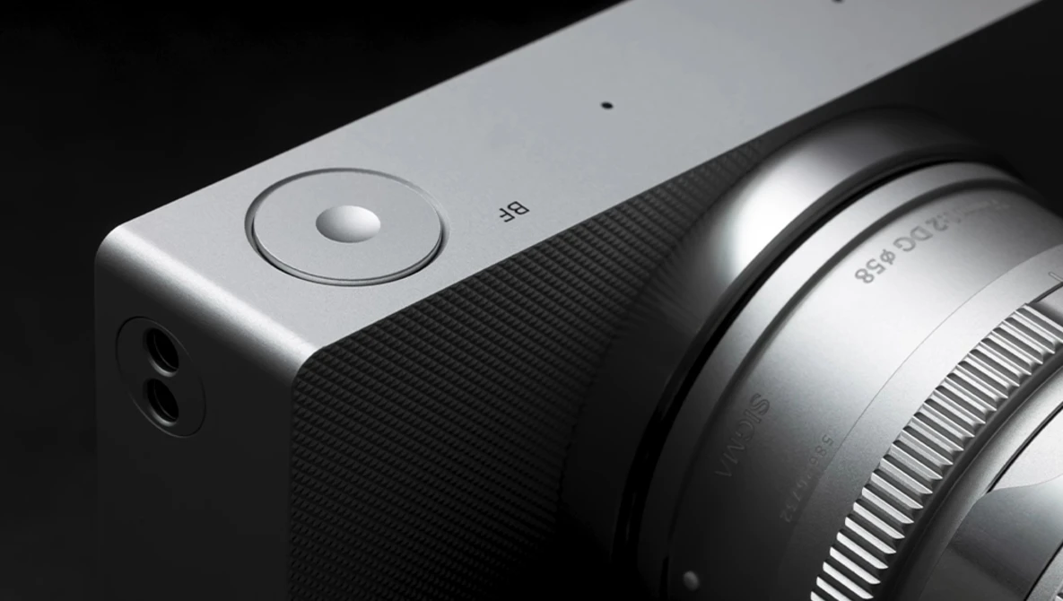Close-up of a mirrorless camera body with attached lens against black background.