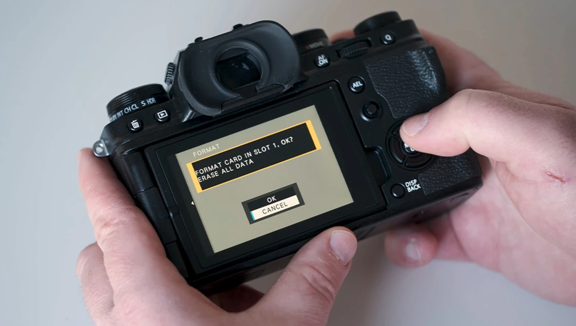 Photographer's hands holding a mirrorless camera displaying a memory card error message on the rear LCD screen.