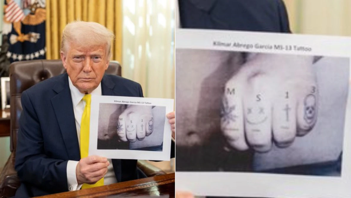 Man in business suit holding up photographs of tattooed knuckles with letters.