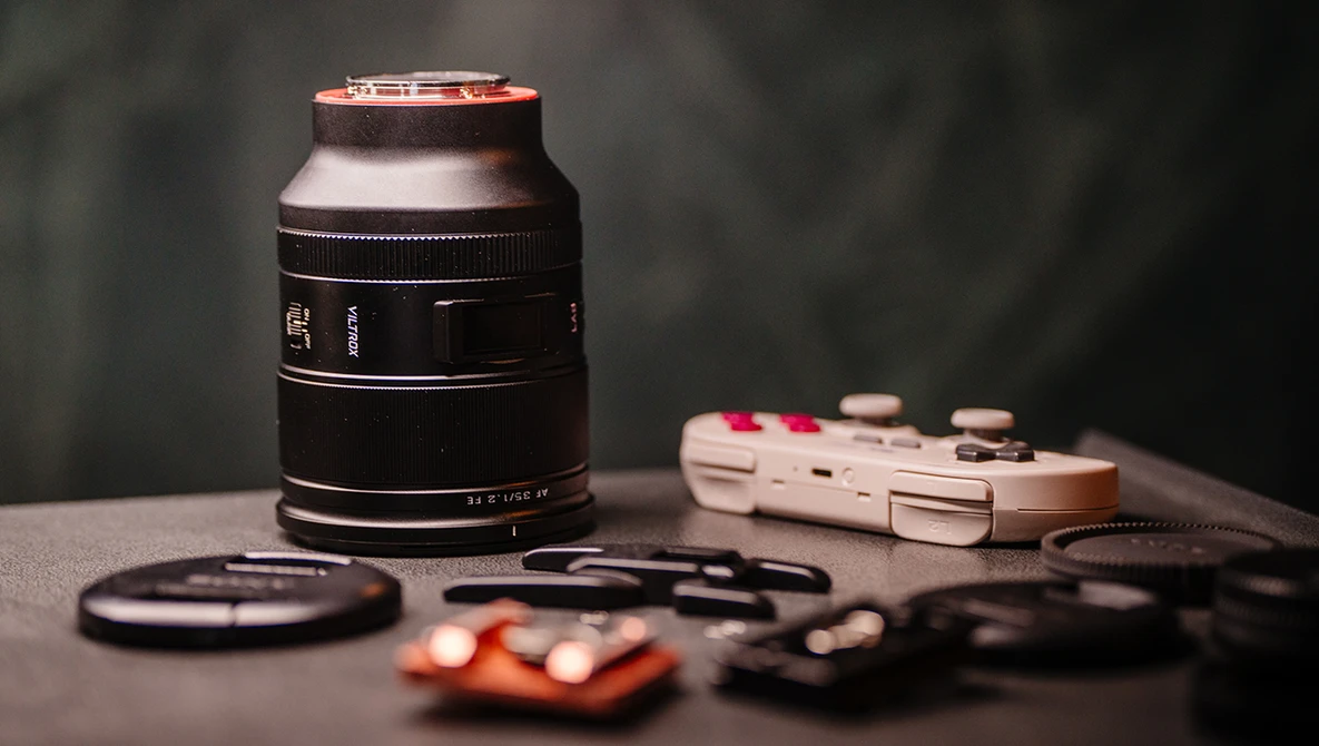 Camera lens and photography accessories arranged on gray surface with selective focus.