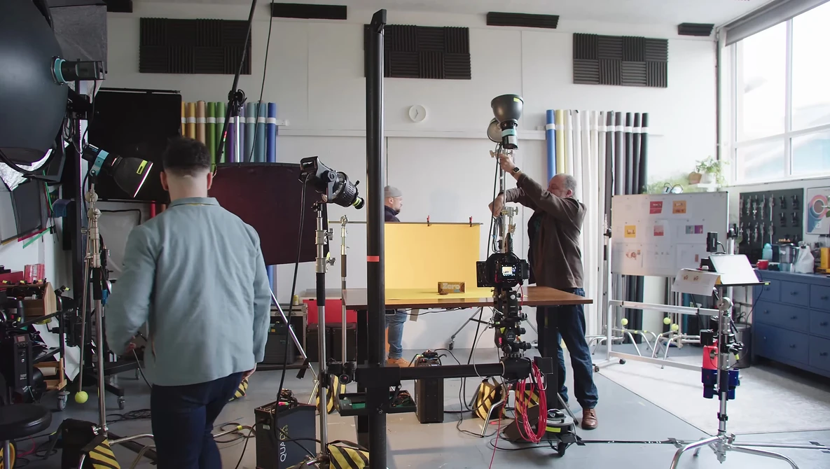 Professional film or photo production studio with crew operating camera equipment and lighting rigs during an active shoot.