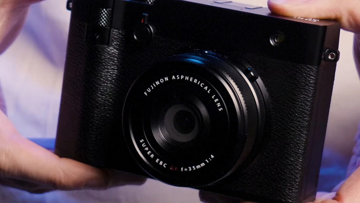 Fujifilm X-Pro1 camera with Fujinon Aspherical lens held in hands during product demonstration.