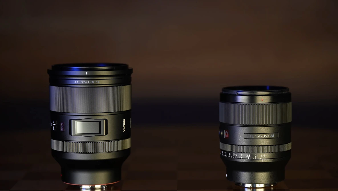 Two camera lenses of different sizes displayed side by side against a dark brown background.