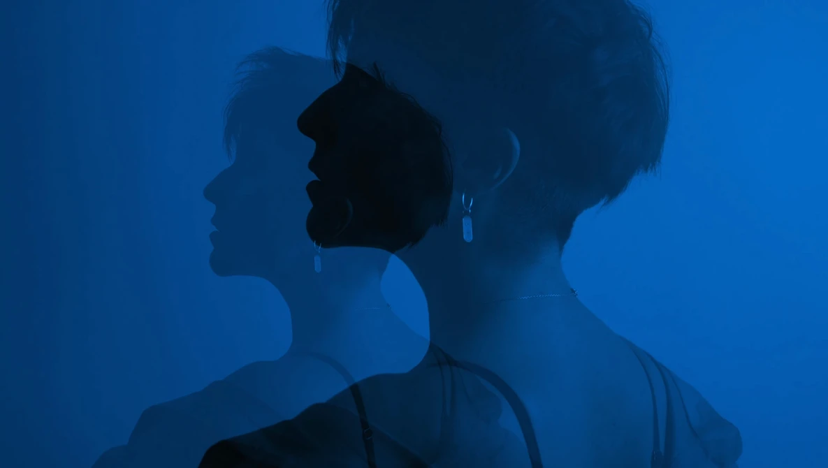 Multiple silhouetted profiles of a woman's face and shoulders overlaid against a deep blue background.