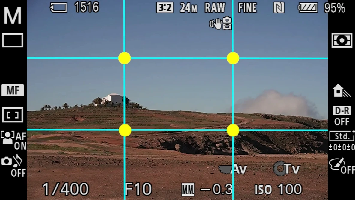 Screenshot of camera viewfinder showing composition grid overlay on arid landscape with distant hills.