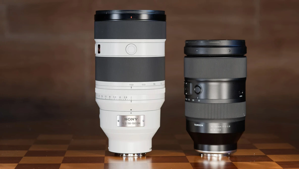 Two telephoto camera lenses side by side on a wooden surface against a brown backdrop.