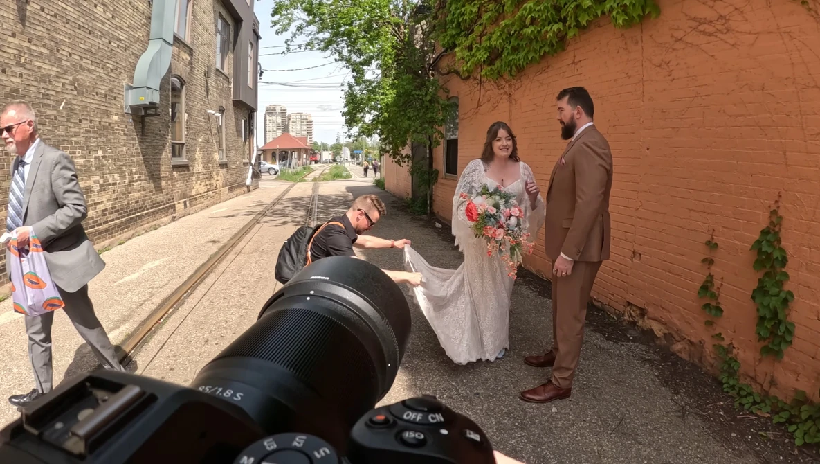 Wedding photography session in an urban alley with a photographer using a telephoto lens in the foreground.