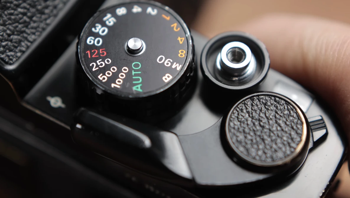 Close-up of vintage camera's top plate showing aperture dial with f-stops and shutter speed settings.