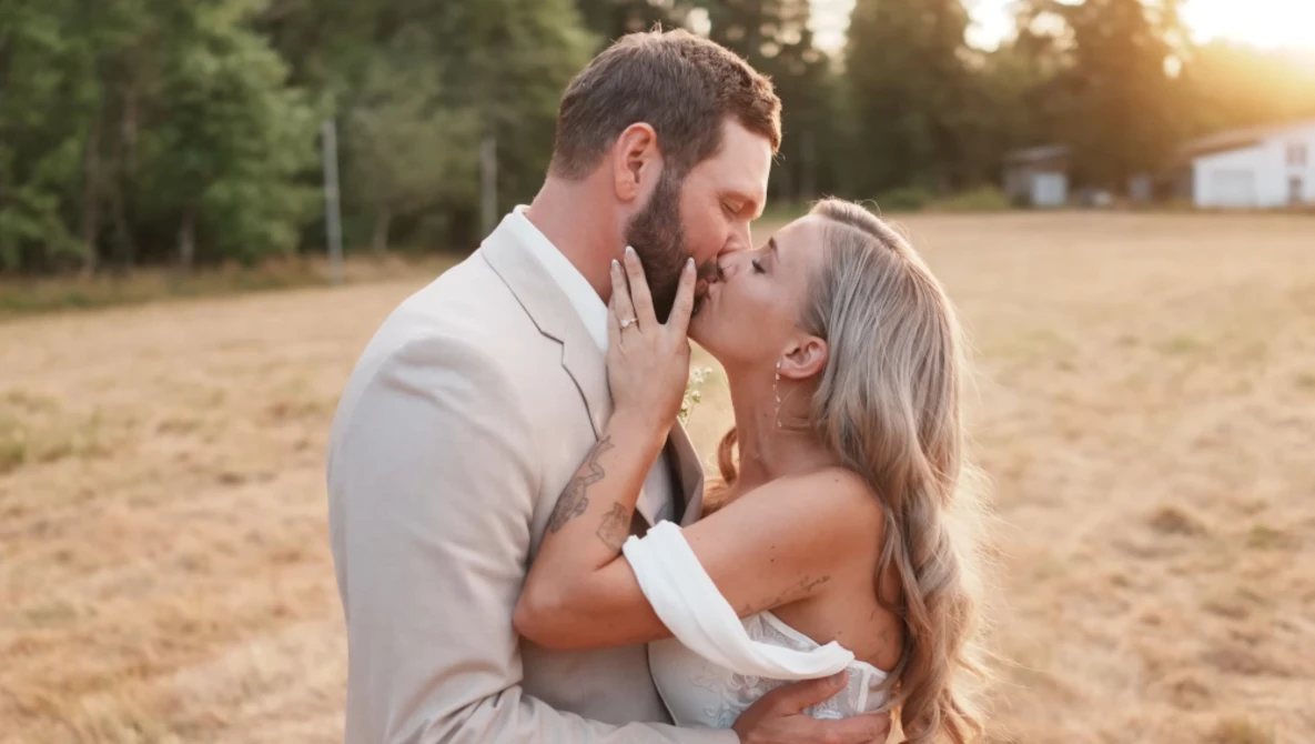 Couple embracing and about to kiss in an open field at golden hour.