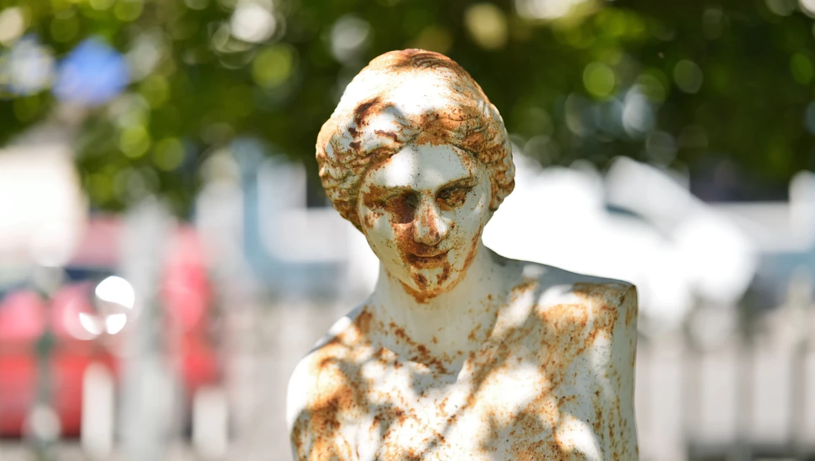 Weathered golden bust sculpture with shallow depth of field and blurred background.