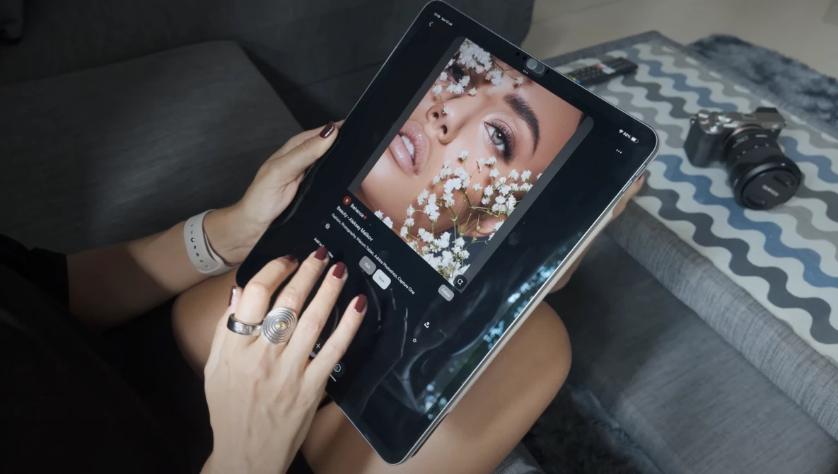 Person holding tablet displaying edited portrait with white powder effect and adjustment controls visible.