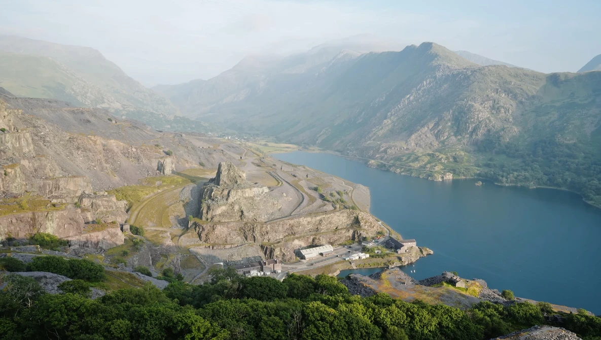 Medieval fortress on a rocky peninsula overlooking a deep blue alpine lake surrounded by mountains.