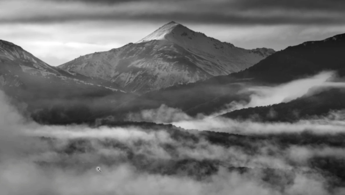Mountain peak rising above a thick blanket of clouds in a misty valley at dawn.
