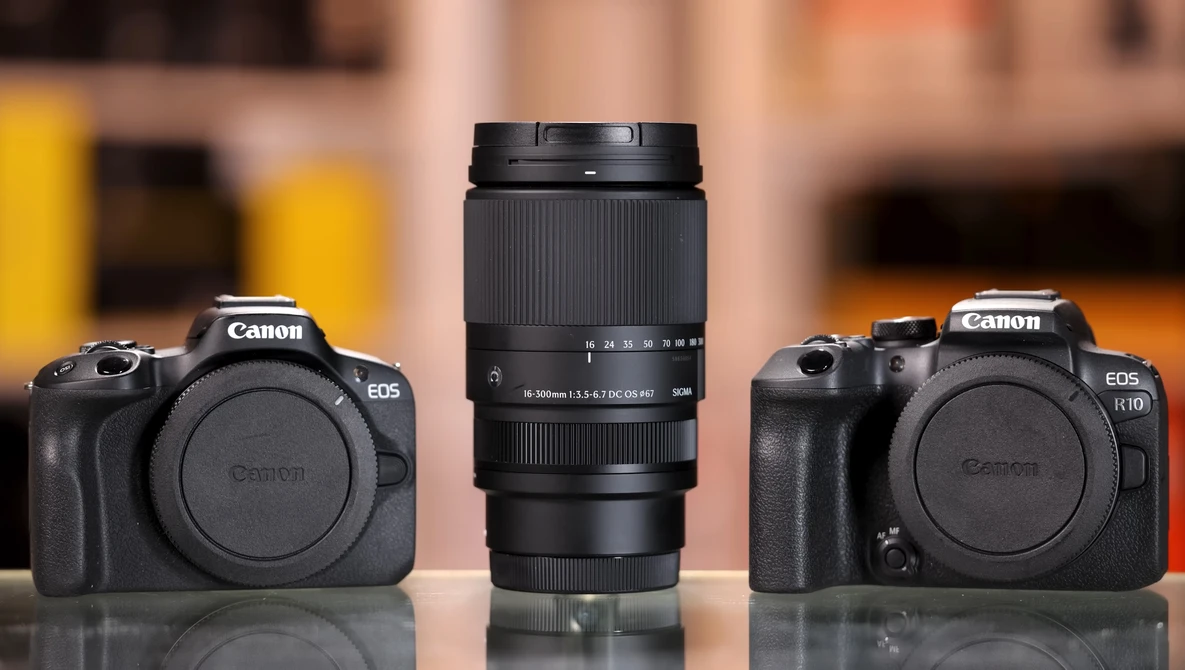 Canon EOS camera body with telephoto zoom lens flanked by two additional camera bodies on reflective surface.
