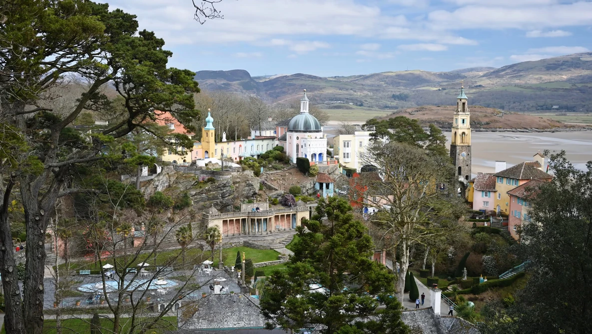 Hilltop monastery with white dome and bell tower overlooking a river valley and mountains.