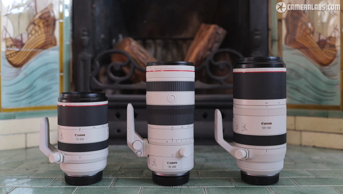 Three Canon RF-mount telephoto lenses with white grip rings displayed side by side on a decorative surface.
