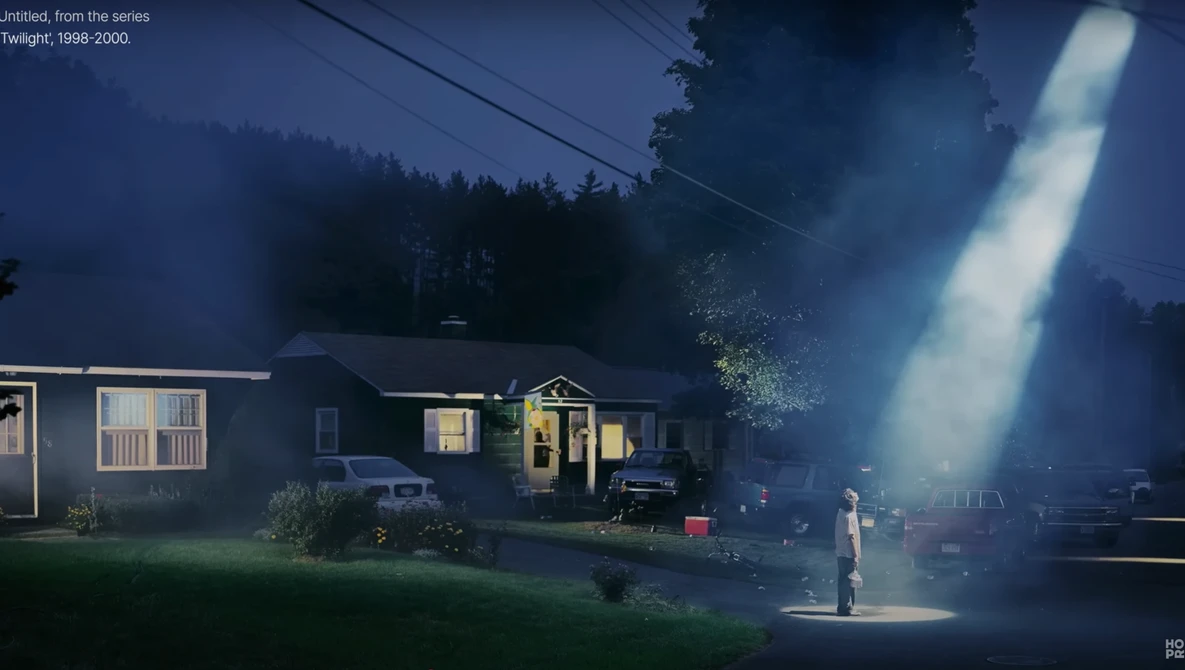 Cinematic nighttime scene of a residential property illuminated by a dramatic shaft of light from above, with forested hills in the background.