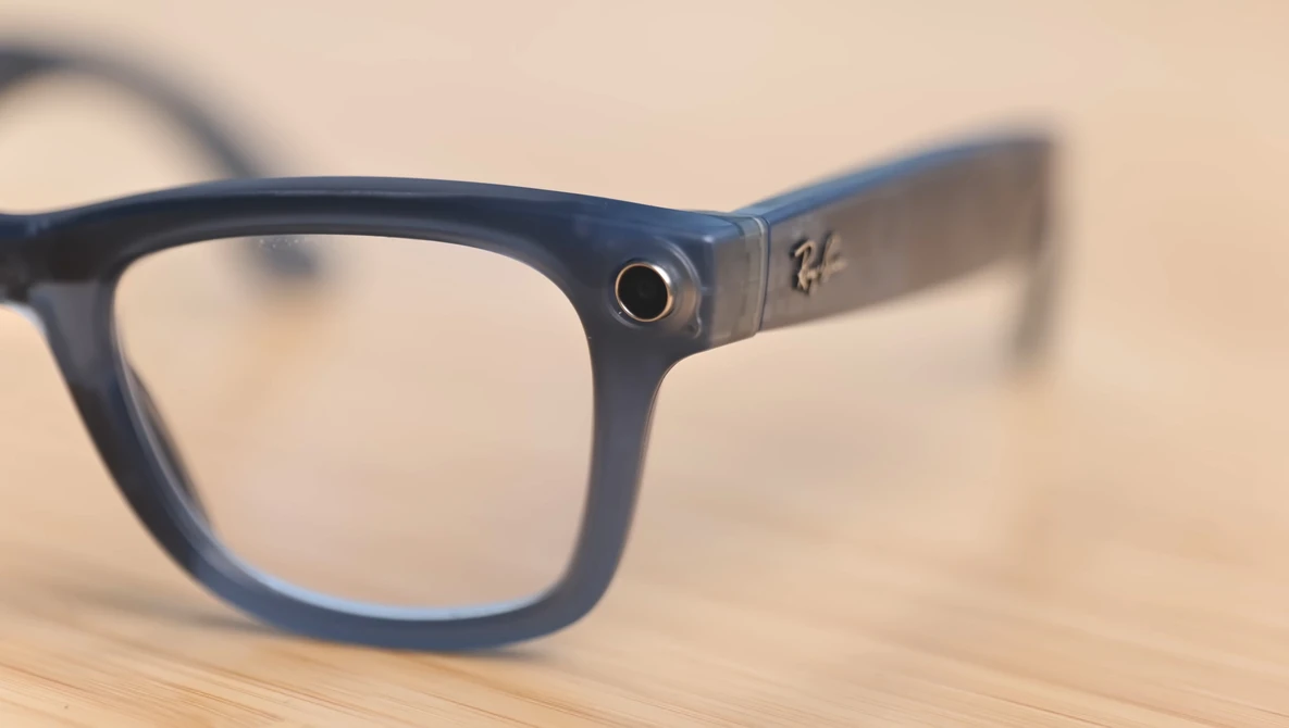 Navy blue wayfarer-style eyeglasses with clear lenses resting on a wooden surface.