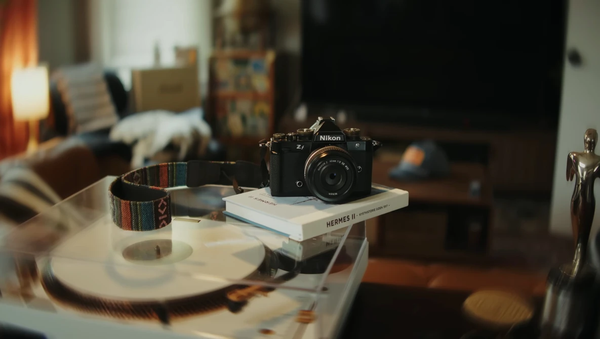 Nikon camera displayed on stacked books atop a round table in a creative workspace.
