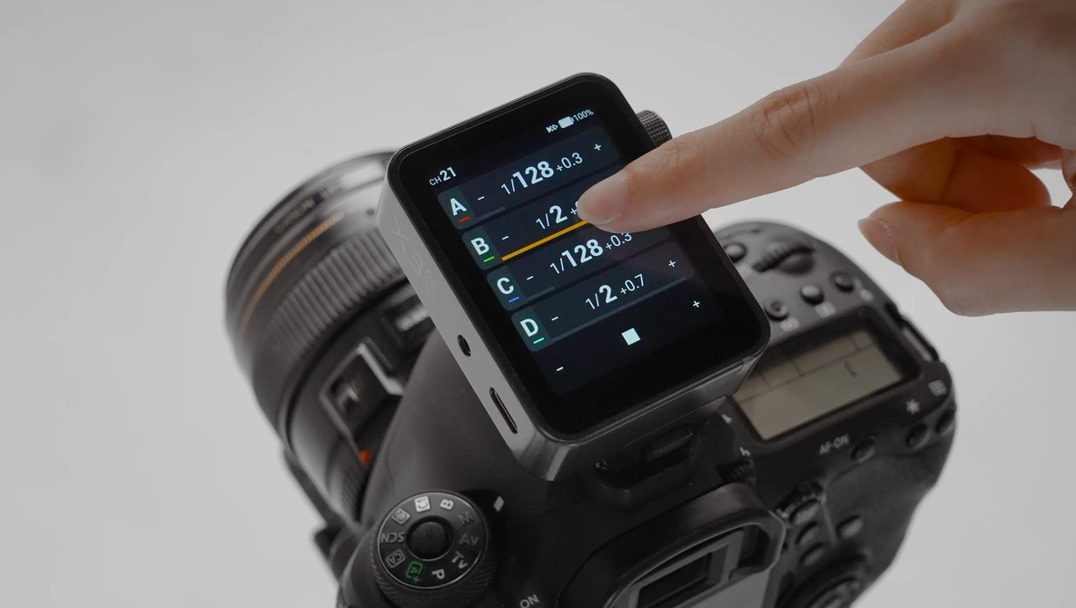 Hand touching smartphone screen displaying camera exposure settings mounted on DSLR camera body.