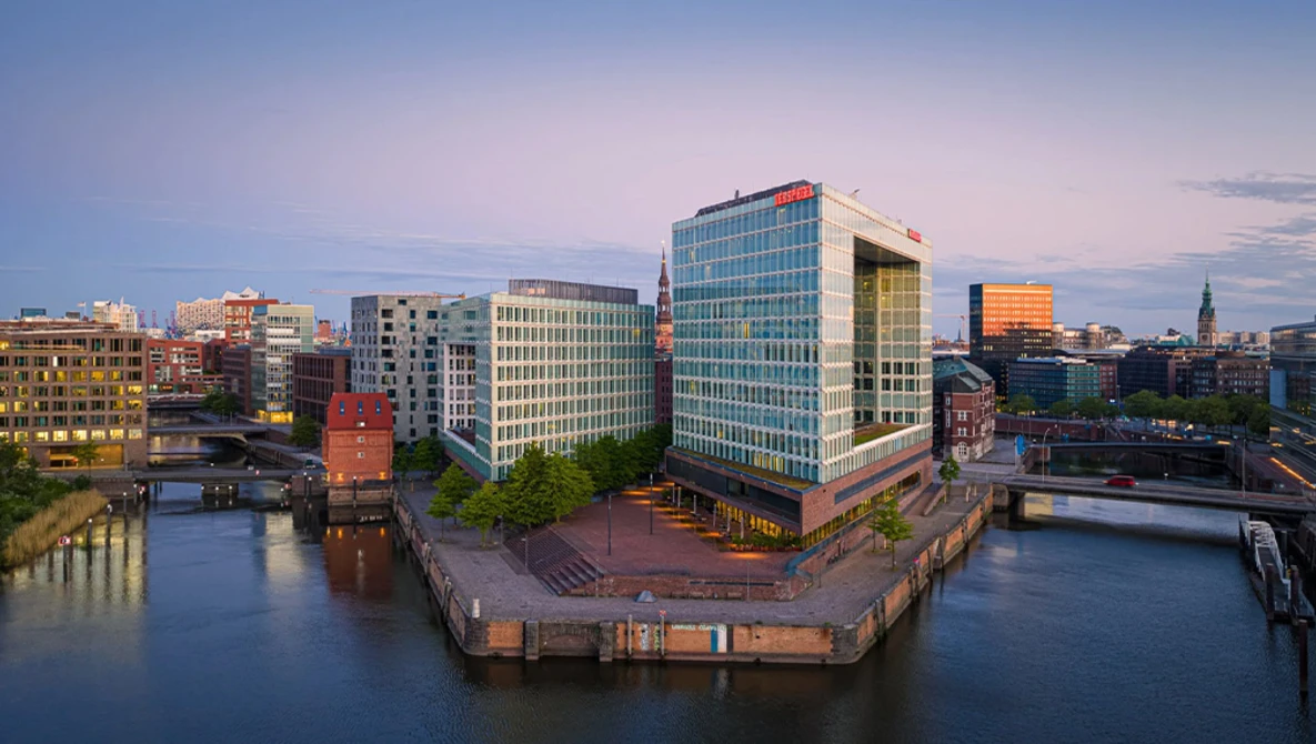 Modern waterfront cityscape at dusk with contemporary office buildings surrounding a central canal basin.