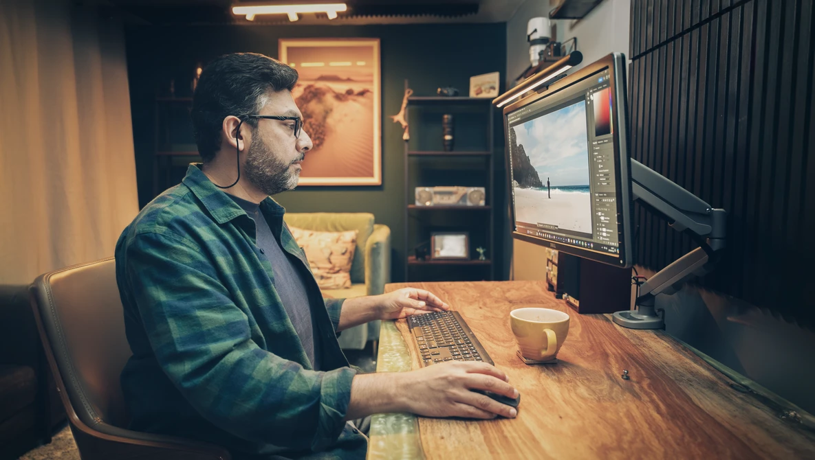 Creative professional editing photos on a desktop computer in a warm-lit home studio setup.