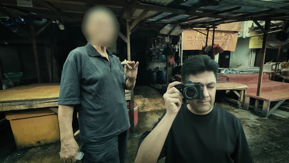 Young photographer holding a vintage film camera in an industrial workshop setting.