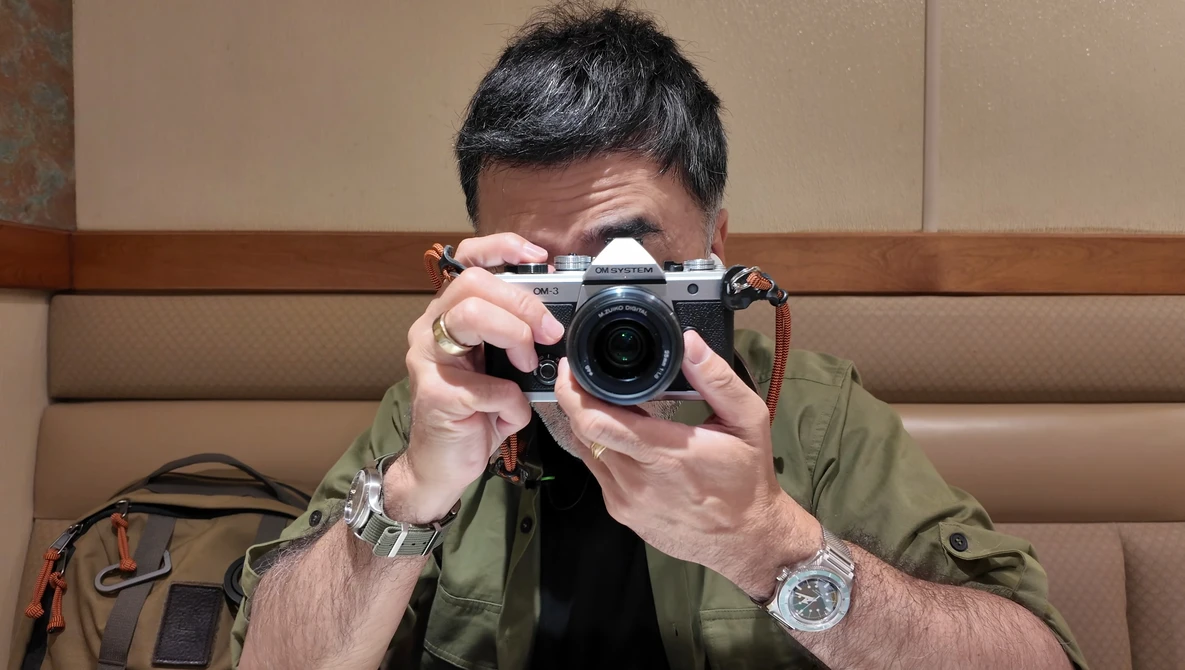 Photographer holding a rangefinder camera up to his face to compose a shot.