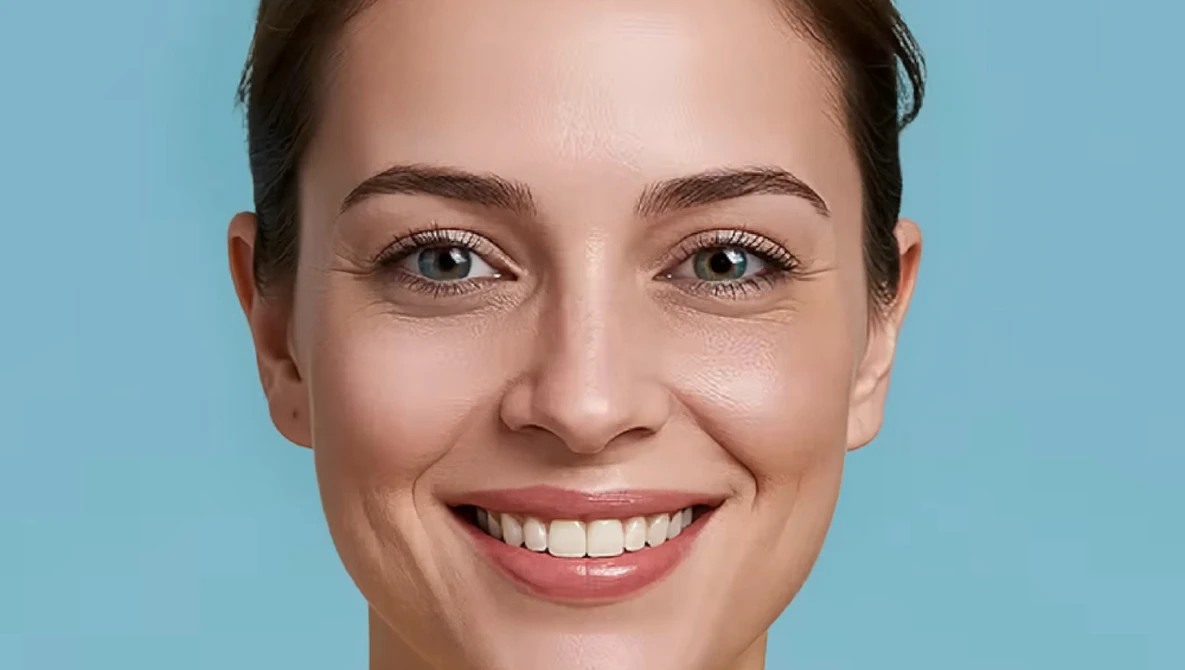 Woman with warm smile looking directly at camera against blue background.