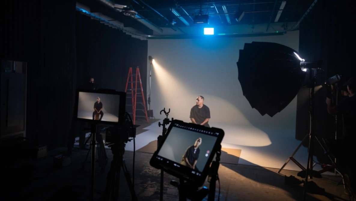 Professional video production set with a subject seated under controlled three-point lighting setup.