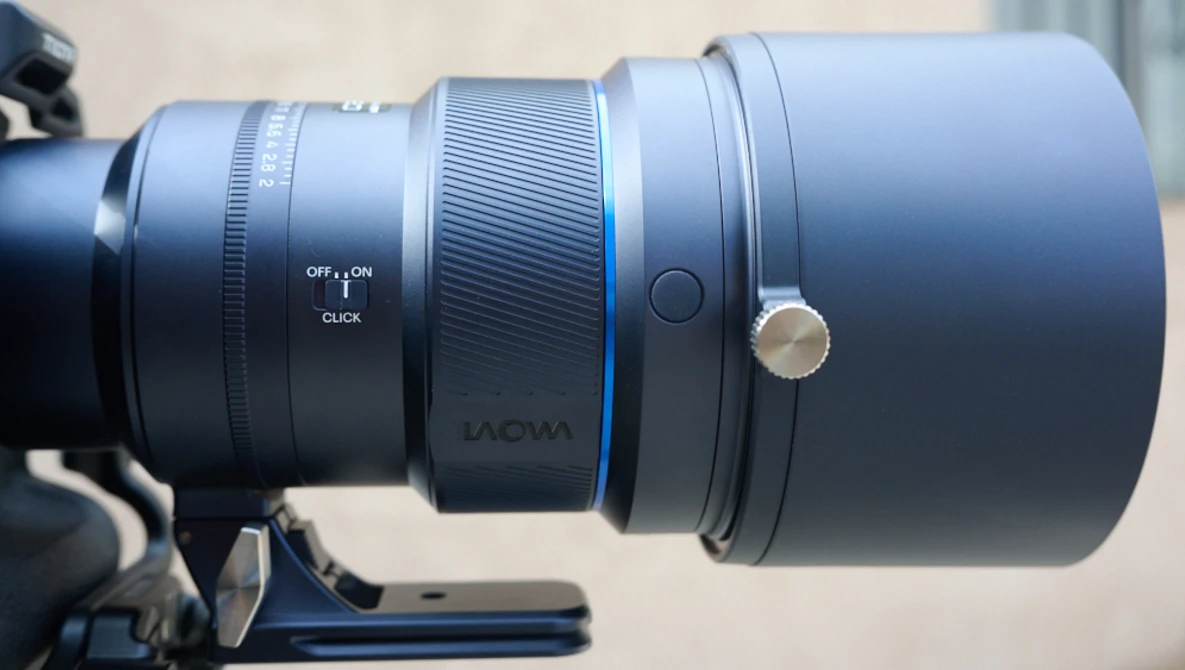 Close-up of a telephoto lens mounted on a camera, showing focus ring, depth of field markings, and manual focus controls.