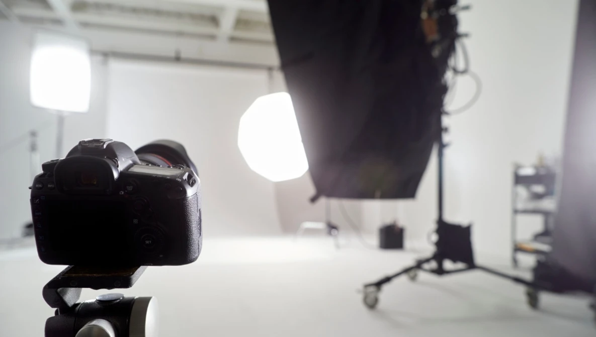 DSLR camera on tripod positioned in studio with bright LED panel lights and reflectors in background.