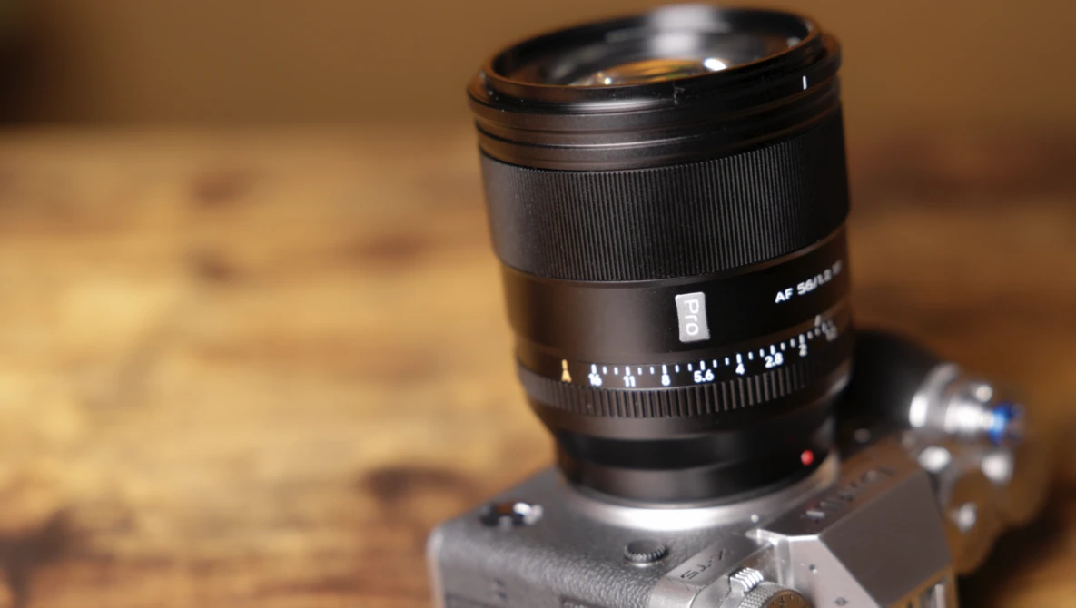 Telephoto lens mounted on vintage rangefinder camera body against wooden surface.