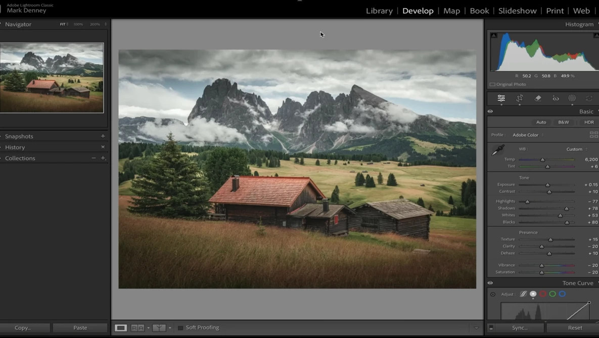 Alpine valley landscape with traditional wooden buildings and dramatic mountain peaks under cloudy sky.