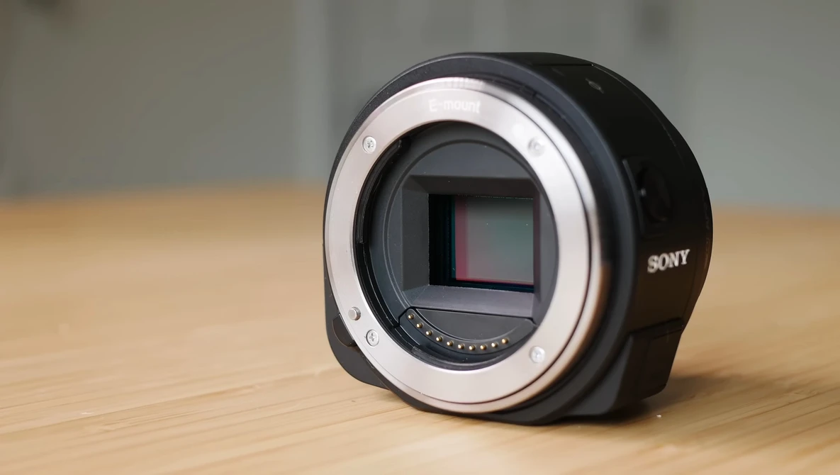 Sony mirrorless camera body without lens, showing sensor and mount ring on wooden surface.