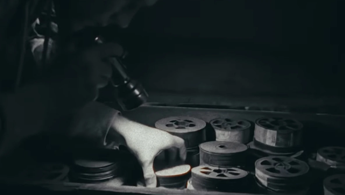 Film reels and storage containers arranged on a surface in dramatic low-key lighting.