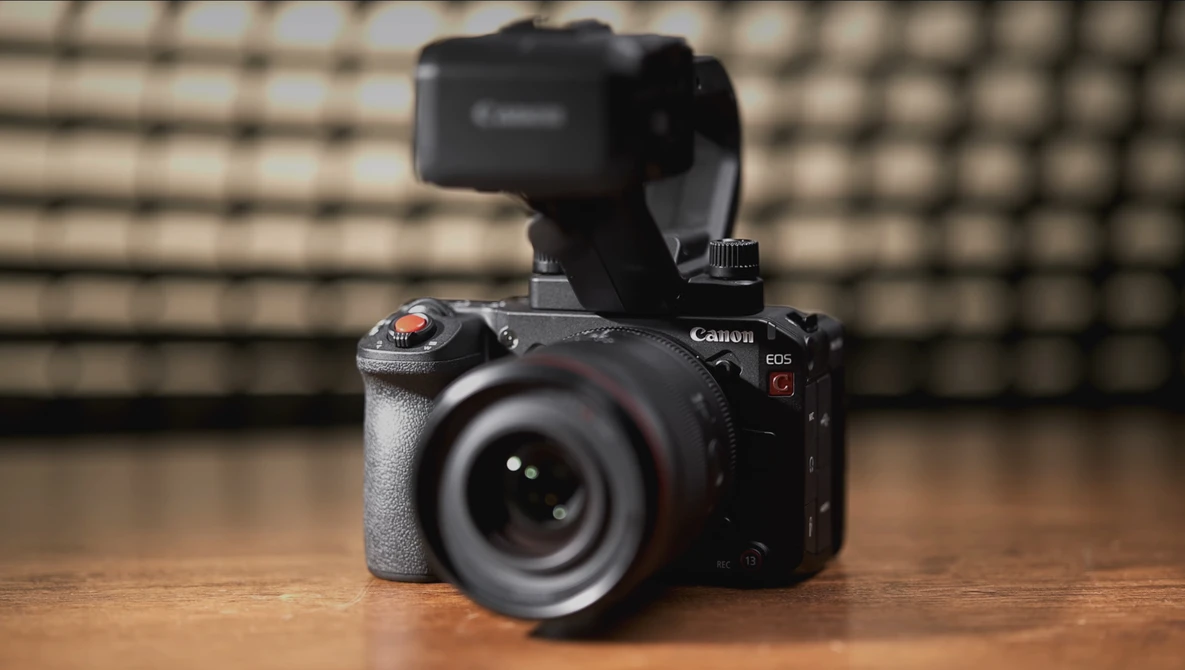 Canon EOS R5 mirrorless camera with external recorder mounted on top, positioned on wooden surface.