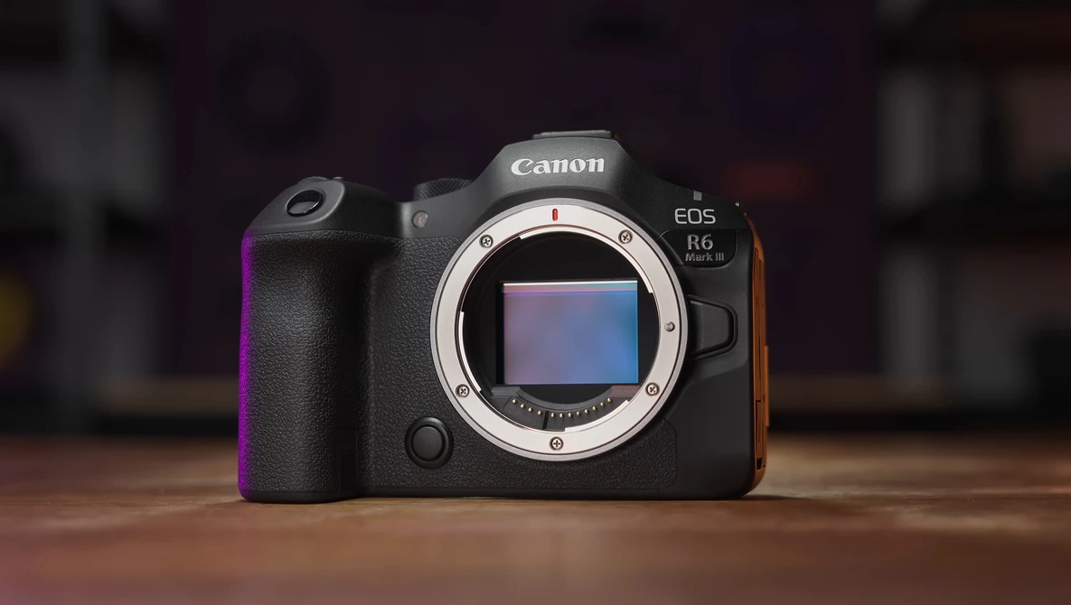 Canon EOS R5 mirrorless camera with lens mount exposed, displayed front-facing on wooden surface.