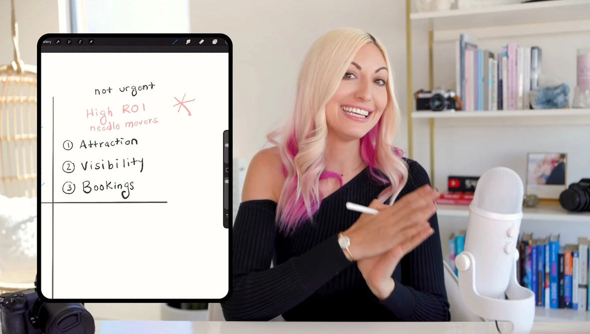 Woman with blonde and pink hair presenting a digital tablet displaying a handwritten list about high ROI priorities including attraction, visibility, and bookings.