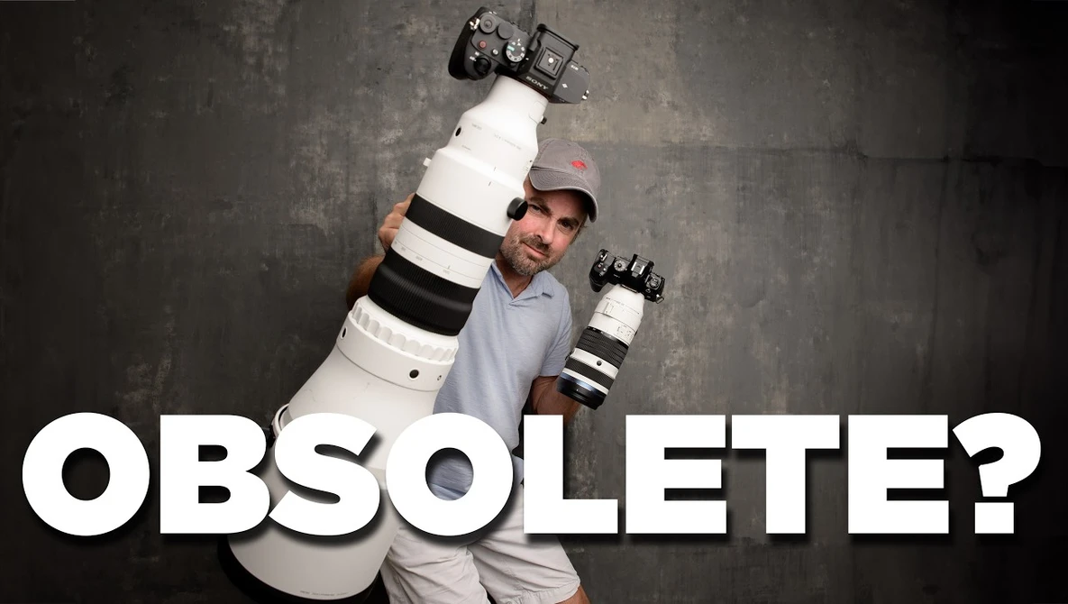 Photographer holding large telephoto lens and camera body overhead against textured gray background.