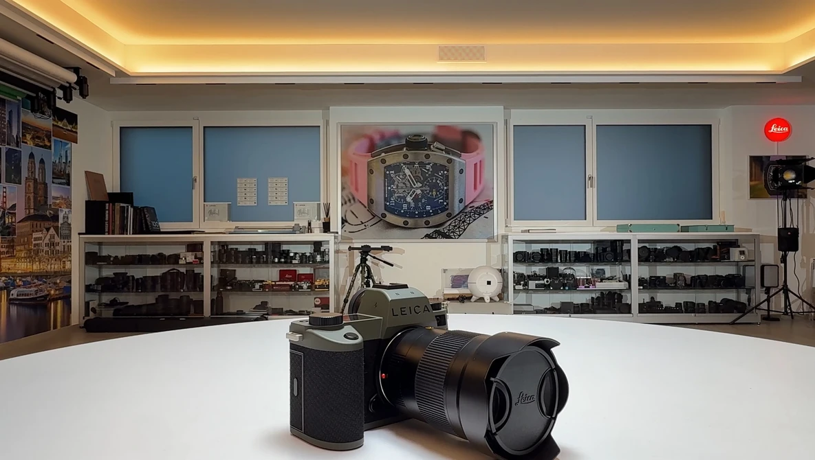 Leica rangefinder camera with telephoto lens displayed on white surface in photography studio.