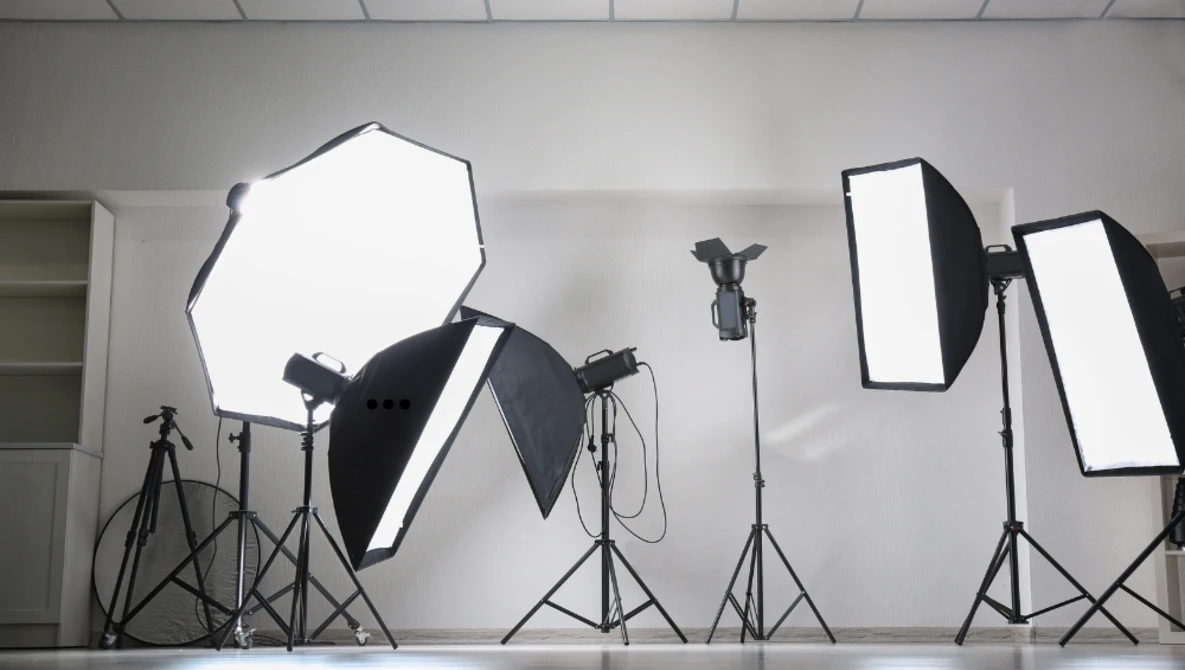Professional studio lighting setup with softboxes, reflectors, and tripod stands arranged in a white studio space.