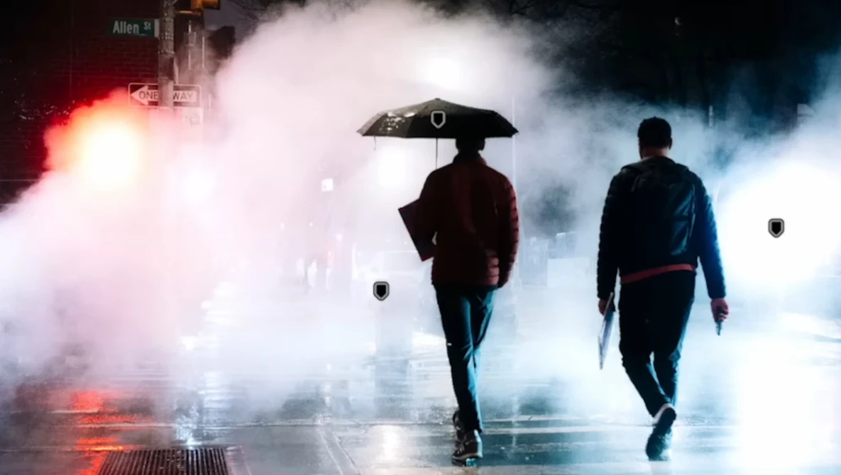 Two figures walking through heavy fog with dramatic red and blue lighting effects on a wet street.