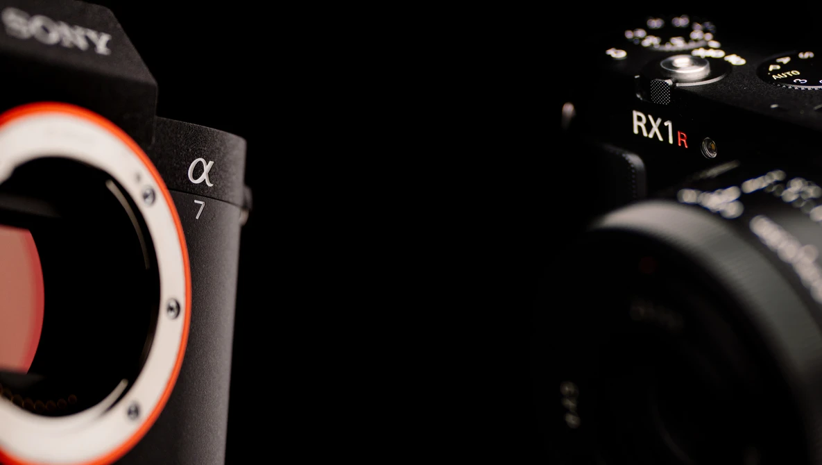 Sony Alpha 7 and RX1R mirrorless cameras positioned against a black background with dramatic side lighting.