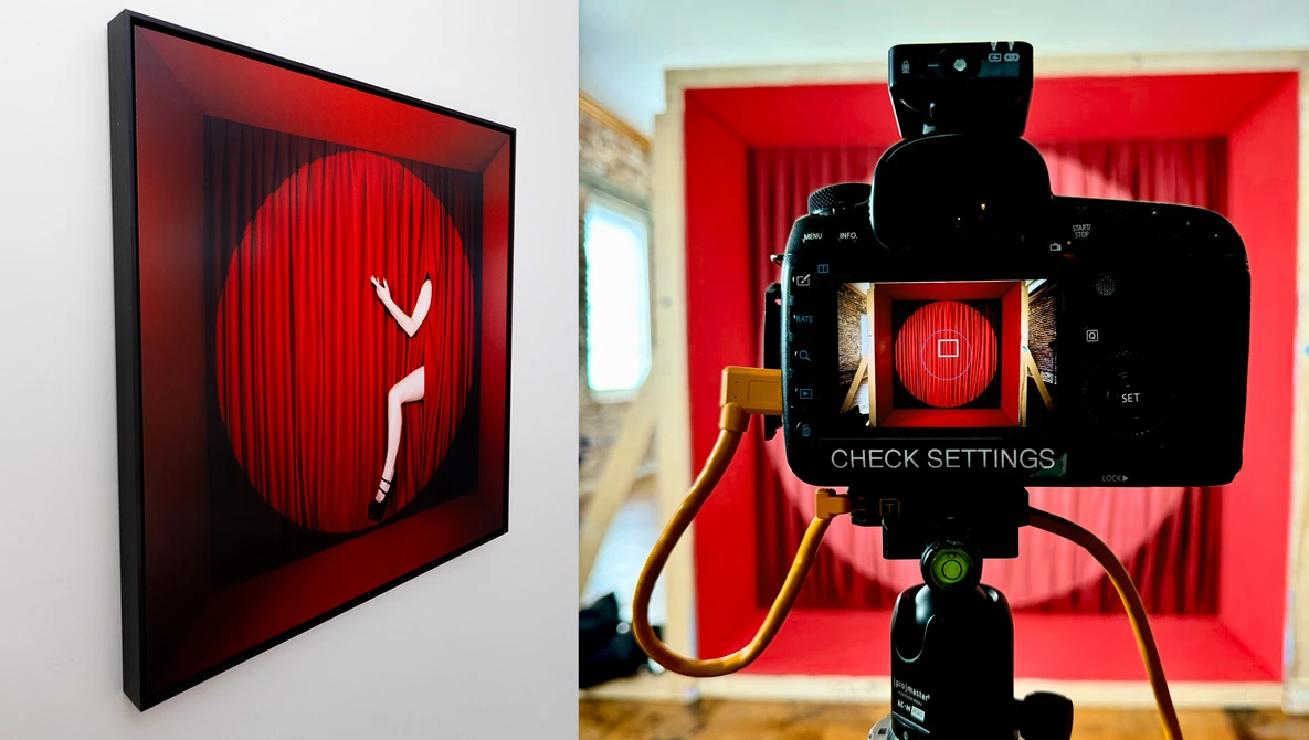 Red neon sign featuring a stylized figure in a phone booth, displayed on gallery wall and viewed through smartphone camera on tripod.