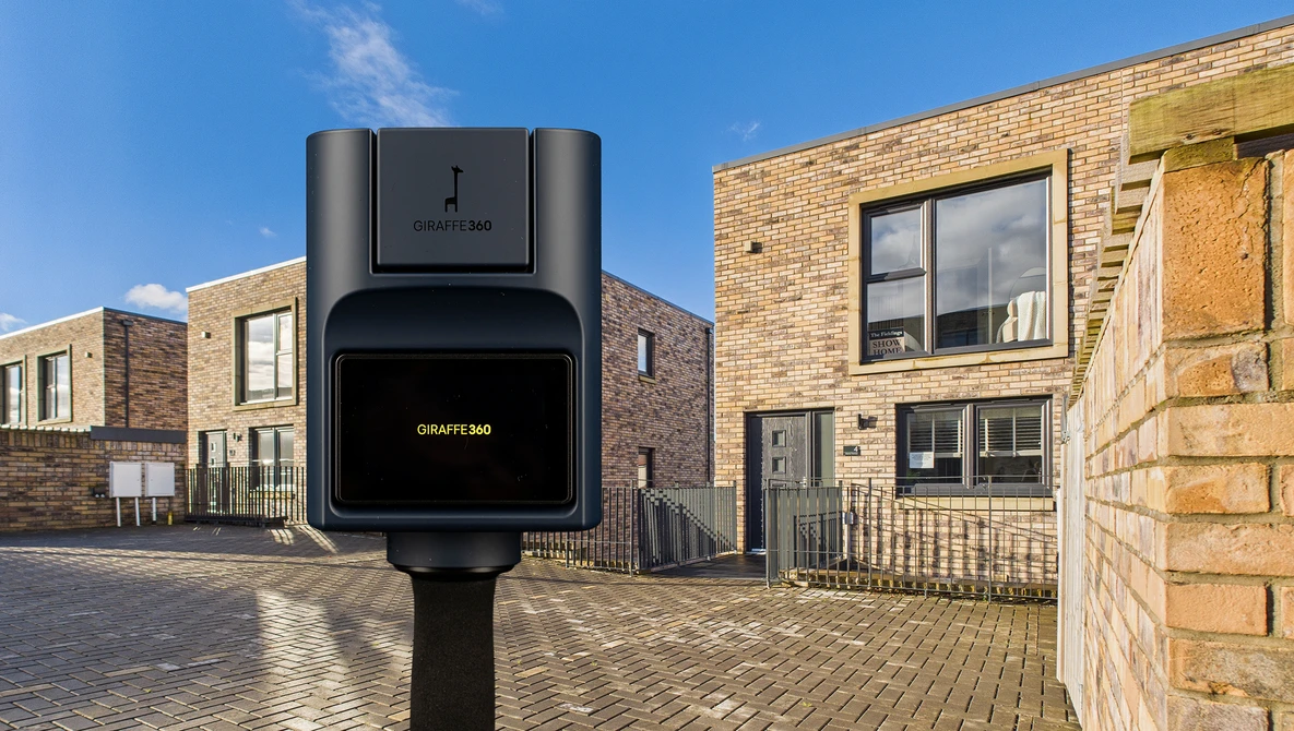 Electric vehicle charging station mounted on pole in residential street with brick buildings.