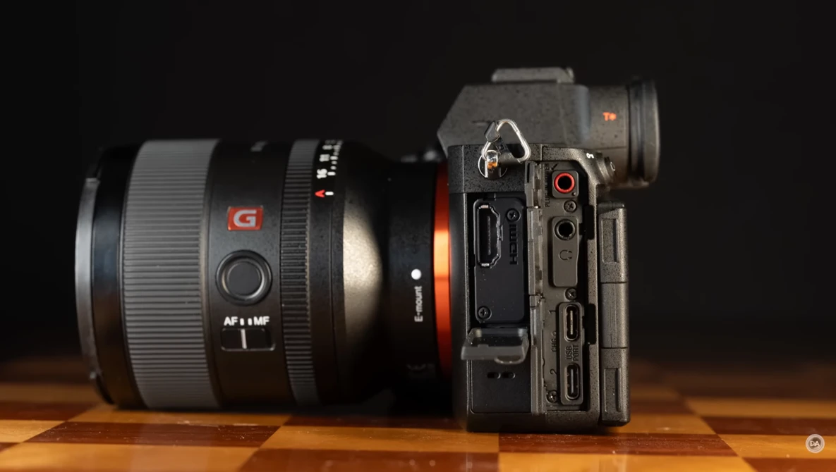 Sony mirrorless camera with attached telephoto lens on wooden surface against dark background.