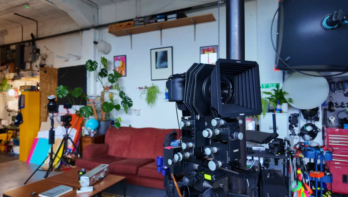 Large format camera mounted on tripod in creative studio workspace.